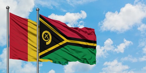 Guinea and Vanuatu flag waving in the wind against white cloudy blue sky together. Diplomacy...