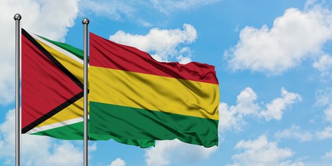 Guyana and Bolivia flag waving in the wind against white cloudy blue sky together. Diplomacy concept, international relations.