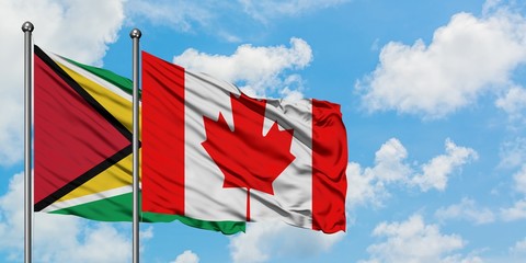Guyana and Canada flag waving in the wind against white cloudy blue sky together. Diplomacy concept, international relations.