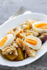 cod fish with sweet potato and boiled egg on white dish on ceramic background
