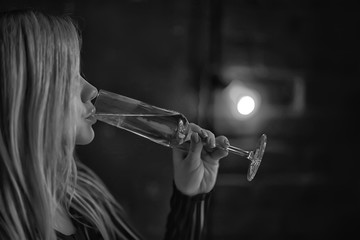 sexy blonde girl drinks champagne from a glass, evening glamorous style portrait