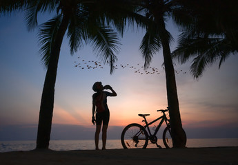 silhouette of woman riding bicycle along the sea beach at sunset, stop drinking water replenish energy