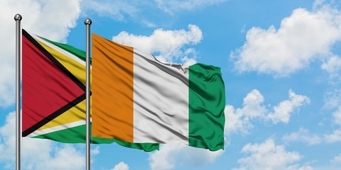 Guyana and Cote D'Ivoire flag waving in the wind against white cloudy blue sky together. Diplomacy concept, international relations.