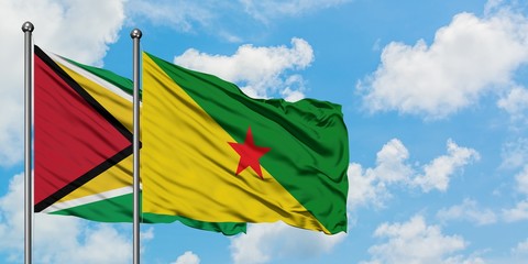 Guyana and French Guiana flag waving in the wind against white cloudy blue sky together. Diplomacy concept, international relations.