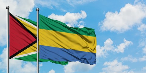 Guyana and Gabon flag waving in the wind against white cloudy blue sky together. Diplomacy concept,...