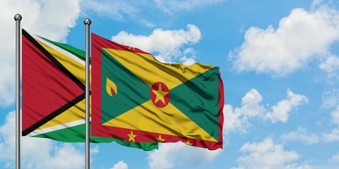 Guyana and Grenada flag waving in the wind against white cloudy blue sky together. Diplomacy concept, international relations.