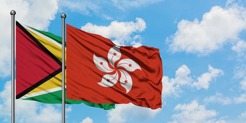 Guyana and Hong Kong flag waving in the wind against white cloudy blue sky together. Diplomacy...