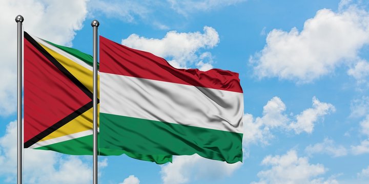 Guyana and Hungary flag waving in the wind against white cloudy blue sky together. Diplomacy concept, international relations.