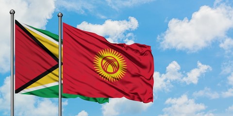 Guyana and Kyrgyzstan flag waving in the wind against white cloudy blue sky together. Diplomacy concept, international relations.