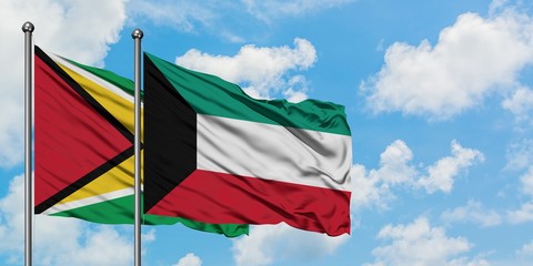 Guyana and Kuwait flag waving in the wind against white cloudy blue sky together. Diplomacy concept, international relations.