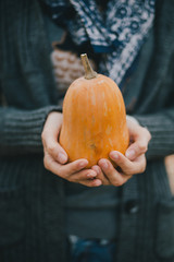 Woman holding small orange pumpkin in her hands