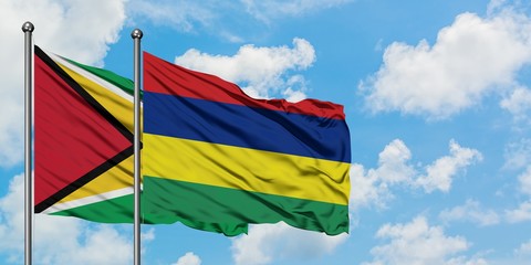 Guyana and Mauritius flag waving in the wind against white cloudy blue sky together. Diplomacy concept, international relations.