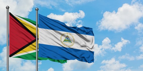 Guyana and Nicaragua flag waving in the wind against white cloudy blue sky together. Diplomacy concept, international relations.