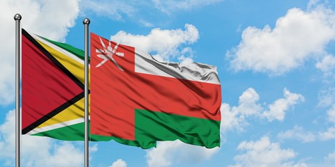 Guyana and Oman flag waving in the wind against white cloudy blue sky together. Diplomacy concept, international relations.