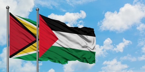Guyana and Palestine flag waving in the wind against white cloudy blue sky together. Diplomacy concept, international relations.