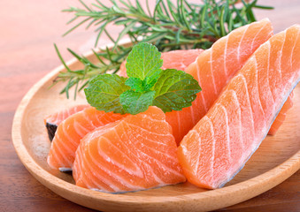 Fresh raw salmon fillet on wooden plate.