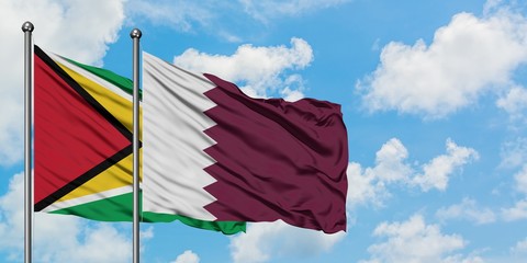 Guyana and Qatar flag waving in the wind against white cloudy blue sky together. Diplomacy concept, international relations.