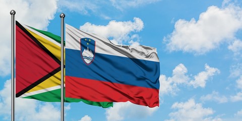 Guyana and Slovenia flag waving in the wind against white cloudy blue sky together. Diplomacy concept, international relations.