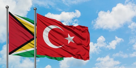 Guyana and Turkey flag waving in the wind against white cloudy blue sky together. Diplomacy concept, international relations.