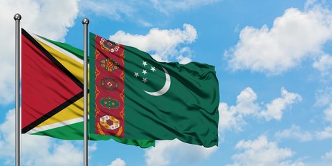 Guyana and Turkmenistan flag waving in the wind against white cloudy blue sky together. Diplomacy...
