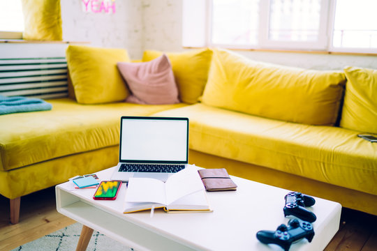 Joysticks And Notebook With Laptop On In Living Room