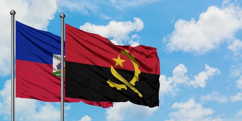 Haiti and Angola flag waving in the wind against white cloudy blue sky together. Diplomacy concept, international relations.