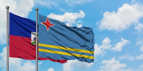 Haiti and Aruba flag waving in the wind against white cloudy blue sky together. Diplomacy concept, international relations.