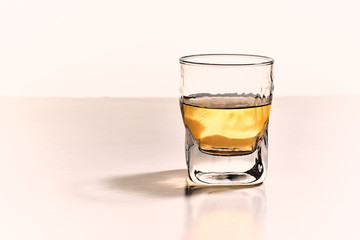 Front view and isolated whiskey glass with golden light