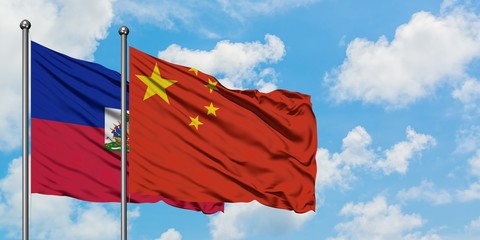 Haiti and China flag waving in the wind against white cloudy blue sky together. Diplomacy concept, international relations.