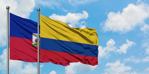 Haiti and Colombia flag waving in the wind against white cloudy blue sky together. Diplomacy concept, international relations.