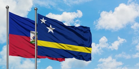 Haiti and Curacao flag waving in the wind against white cloudy blue sky together. Diplomacy concept, international relations.