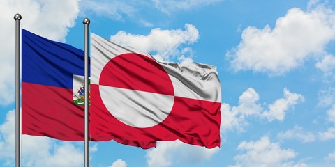 Haiti and Greenland flag waving in the wind against white cloudy blue sky together. Diplomacy...