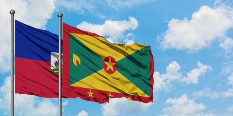 Haiti and Grenada flag waving in the wind against white cloudy blue sky together. Diplomacy concept, international relations.