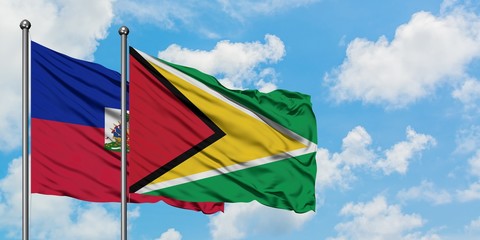 Haiti and Guyana flag waving in the wind against white cloudy blue sky together. Diplomacy concept, international relations.