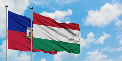 Haiti and Hungary flag waving in the wind against white cloudy blue sky together. Diplomacy concept, international relations.