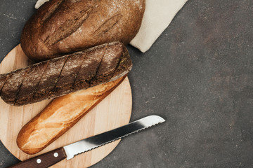  Loafs of rye and wheat bread on a wooden board and knife. Fresh crisp bread.