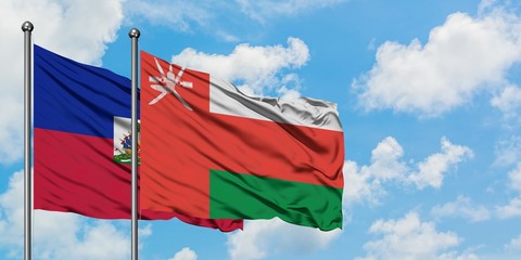 Haiti and Oman flag waving in the wind against white cloudy blue sky together. Diplomacy concept, international relations.