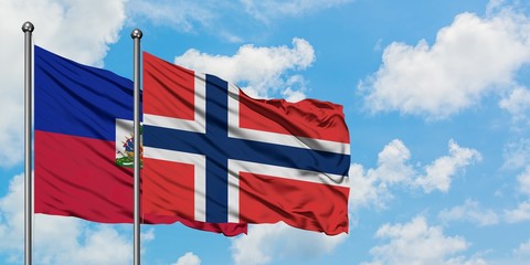 Haiti and Norway flag waving in the wind against white cloudy blue sky together. Diplomacy concept, international relations.