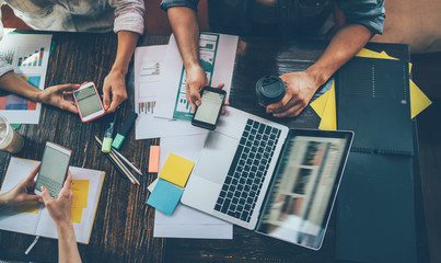 Crop colleagues with smartphones at cafe table