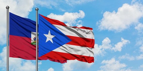 Haiti and Puerto Rico flag waving in the wind against white cloudy blue sky together. Diplomacy concept, international relations.