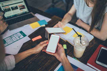 Crop colleagues with smartphones in cafe