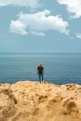 Hombre de sombrero en acantilado con horizonte de mar oceánico en paz respirando tranquilo sosegado
