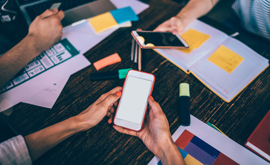 Faceless students with smartphones in cafe