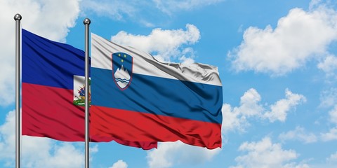 Haiti and Slovenia flag waving in the wind against white cloudy blue sky together. Diplomacy concept, international relations.