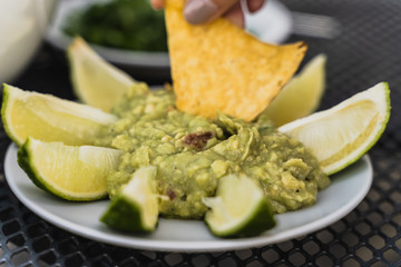 Mexican Guacamole dip with lime slices and doritos or nachos crisps