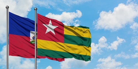 Haiti and Togo flag waving in the wind against white cloudy blue sky together. Diplomacy concept, international relations.