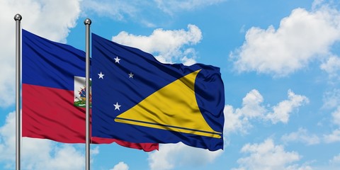 Haiti and Tokelau flag waving in the wind against white cloudy blue sky together. Diplomacy concept, international relations.