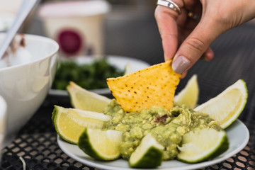 Mexican Guacamole dip with lime slices and doritos or nachos crisps