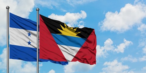 Honduras and Antigua and Barbuda flag waving in the wind against white cloudy blue sky together. Diplomacy concept, international relations.