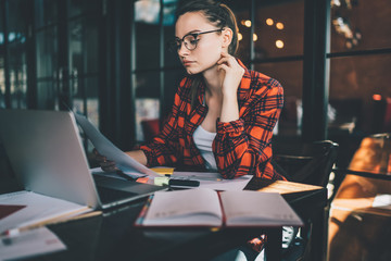 Smart woman reading papers sitting in cafe